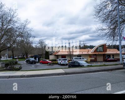 Lynnwood, WA USA - ca. März 2022: Blick auf die Straße eines McDonalds-McDonalds, der mit Autos gefüllt ist und an einem bewölkten Tag auf ihr Essen wartet. Stockfoto