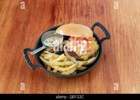 Käseburgerfleisch wird mit knusprigen Gurken, gehackten Zwiebeln, Ketchup, Senf und einer Scheibe geschmolzenem amerikanischen Käse gekrönt Stockfoto