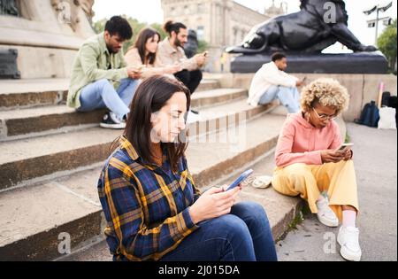 Die Gruppe der technologieabhängigen Menschen ignoriert sich gegenseitig, indem sie Mobile nutzen. Individualistische Menschen chatten mit dem Smartphone Stockfoto