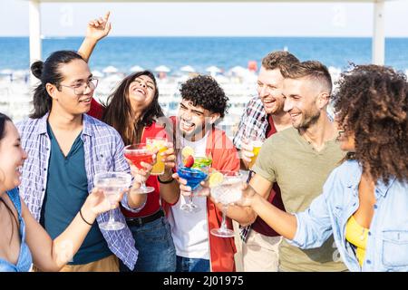 Glückliche multirassische Freunde, die Spaß haben, Cocktails auf der Sommerparty zu trinken Stockfoto