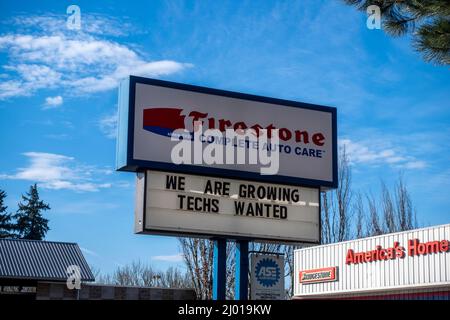 Woodinville, WA USA - ca. Februar 2022: Low-Angle-Ansicht eines Now Hiring-Zeichens an einem Firestone Auto Care an einem hellen sonnigen Tag. Stockfoto