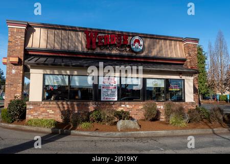 Woodinville, WA, USA - ca. Februar 2022: Selektiver Fokus auf ein "Jetzt einstellen"-Schild in einem Wendy's Fast Food Restaurant-Fenster an einem hellen, sonnigen Tag. Stockfoto