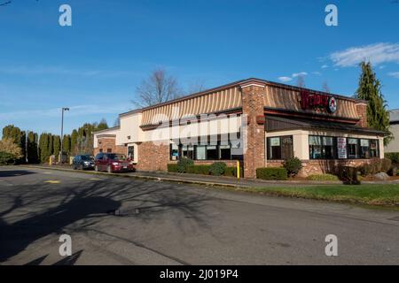 Woodinville, WA USA - ca. Februar 2022: Schräge Ansicht der Autos, die im Drive-Thru-Fenster aufgereiht waren und in Wendys Fast-Food-Restaurant auf ihre Bestellung warteten Stockfoto