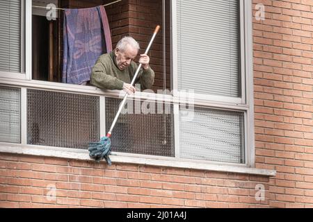 Burgos, Spanien. 15. März 2022. Ein älterer Mann reinigt die Fensterbank mit einem Wischmopp, während die Stadt Burgos mit Autos, Böden und Dächern aufwacht, die durch den Dunst mit Sand bedeckt sind. Kredit: SOPA Images Limited/Alamy Live Nachrichten Stockfoto