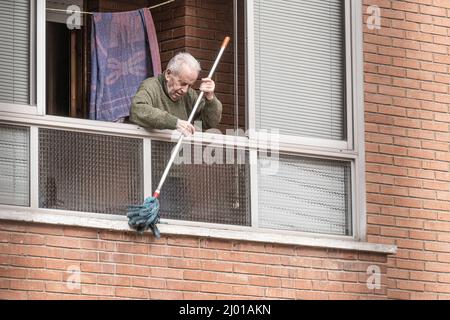 Burgos, Spanien. 15. März 2022. Ein älterer Mann reinigt die Fensterbank mit einem Wischmopp, während die Stadt Burgos mit Autos, Böden und Dächern aufwacht, die durch den Dunst mit Sand bedeckt sind. (Foto: Jorge Contreras Soto/SOPA IMAG/Sipa USA) Quelle: SIPA USA/Alamy Live News Stockfoto