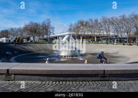 Seattle, WA USA - ca. März 2022: Blick auf einen Vater und seine Kinder, die mit dem Fahrrad um den Internationalen Brunnen in der Nähe der Space Needle fahren Stockfoto