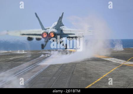 Philippine Sea, Vereinigte Staaten. 15. März 2022. Ein F/A-18E Super Hornet Kampfjet der US Navy, der dem Kampfjet Tophatters of Strike Fighter Squadron 14 zugewiesen wurde, startet während des Routinebetriebs am 9. März 2022 in der philippinischen See vom Flugdeck des Flugzeugträgers USS Abraham Lincoln der Nimitz-Klasse. Kredit: MC3 Javier Reyes/Planetpix/Alamy Live Nachrichten Stockfoto