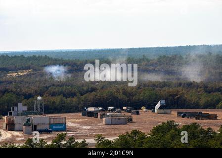 Trümmer aus der Munitionsanlage der US Air Force A-10 Thunderbolt II, mit der 104.-Kampfschürze des 175.-Flügels, Maryland Air National Guard, ragt am 10. März 2022 in der Warren Grove Gunnery Range, Warren Grove, New Jersey, über die Baumgrenze. Brig. General Patrick M. Kennedy, Assistant Adjutant General-Air, New Jersey National Guard, und Chief Master Sgt. Michael J. Rakauckas, Kommandochef der New Jersey Air National Guard, beobachtete das Training während eines Besuchs. (USA Foto der Air National Guard von Senior Airman Hunter Hires) Stockfoto