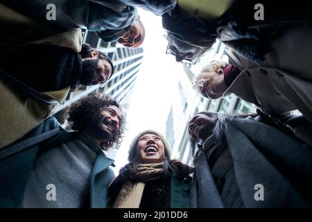 Niedriger Winkel einer Einheit Gruppe von Geschäftsleuten im Kreis. Kollegen mit einem fröhlichen Lächeln. Gemeinschaft verschiedener alter und multirassischer Teamarbeit Stockfoto