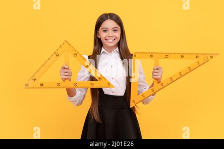 Lächelndes Teenager-Mädchen halten Dreieck. Zurück zur Schule. Algebra und Geometrie. Kind Mathematik lernen. Stockfoto