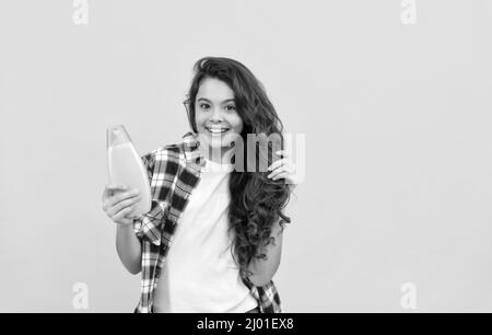 Präsentieren kosmetisches Produkt. Schönheit. Kind verwenden Duschgel. Happy teen Mädchen mit Shampoo-Flasche. Stockfoto