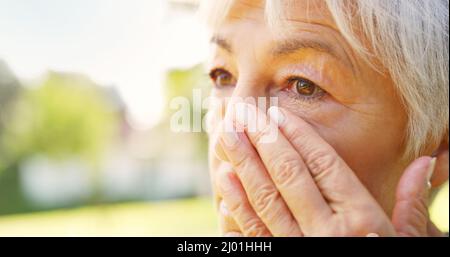 Sie wird tränenig, wenn sie ihren geliebten Menschen vermisst. Nahaufnahme einer traurigen älteren Frau, die draußen Tränen von ihrem Gesicht wischte. Stockfoto