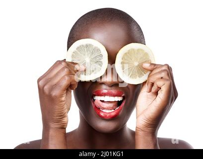 Wenn das Leben Hände Zitronen, handeln Sie der Narr. Studioaufnahme eines wunderschönen Models, das Zitronenscheiben vor die Augen hält. Stockfoto