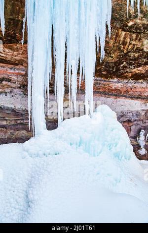 Riesige Eiszapfen auf Klippen bilden einen Haufen von Eisklumpen Stockfoto
