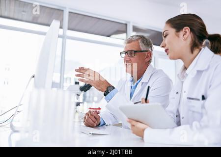 Effizienz in ihrem Labor mit modernster Technologie. Aufnahme von zwei Wissenschaftlern, die in einem Labor an einem Computer zusammenarbeiten. Stockfoto