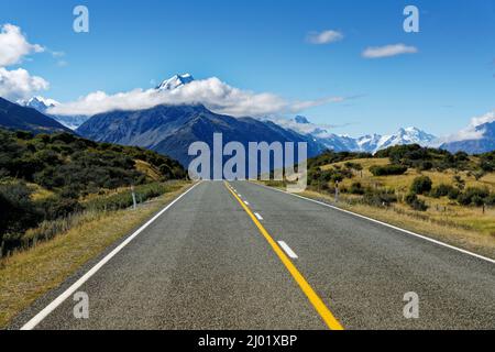 Die Straße, die zum Mount Cook Village führt, Mt Cook im Hintergrund mit Wolken um den Gipfel, Südinsel, Aotearoa / Neuseeland. Stockfoto