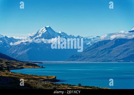 Blick über einen leuchtend türkisfarbenen Lake Pukaki zum Mt Cook, Wolken um den Gipfel, Aoraki/Mount Cook National Park, Südinsel, Aotearoa/Neuseeland. Stockfoto