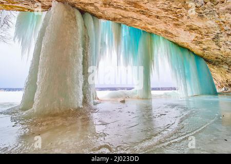 Gefrorener Wasserfall am See in der Höhle mit blauen Eiszapfen Stockfoto