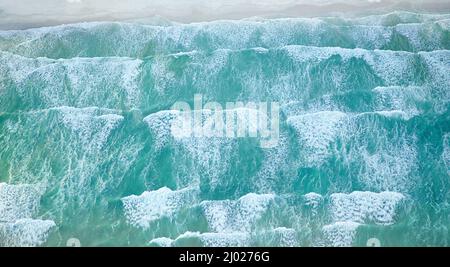 Ebbe und Flut des Meeres. Luftaufnahme der Meereswellen, die sich zur Küste hin bewegen. Stockfoto