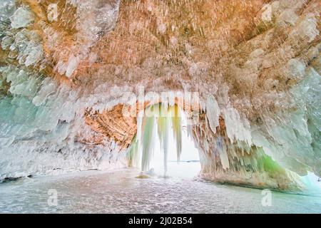 Majestätische Eiskristall-Höhle auf gefrorenem See mit blauen und grünen Eiszapfen Stockfoto