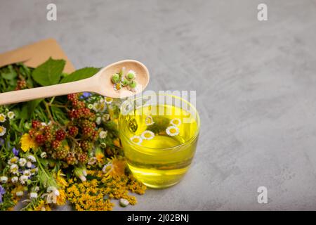 Glas Tasse heißen Tee auf grauem Tisch. Kamillentee in Glasbecher. Stockfoto