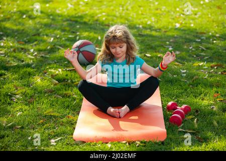 Kind, das im Freien Sport macht. Gesunder Kinderlebensstil. Yoga Kinder im Park machen Yoga Asana. Lifestyle Entspannungskonzept, sommerliche Harmonie im Freien Stockfoto