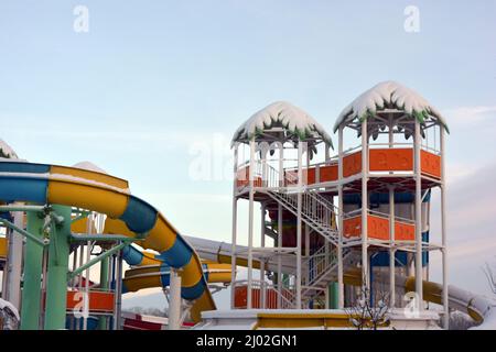 Ein schönes und helles Bild von Entspannung und Unterhaltung. Schöne wassergelbe, blaue, farbige und helle Rutschen mit Palmenabdeckung aus Kunststoff Stockfoto