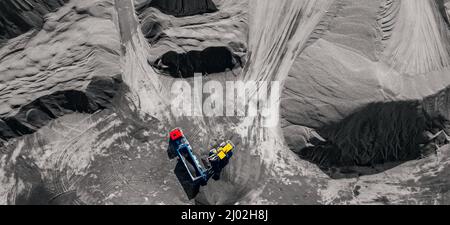 Industrieller Bannerbagger, der Stein, Schotter oder Sand in LKW verladen kann. Luftaufnahme von oben. Stockfoto
