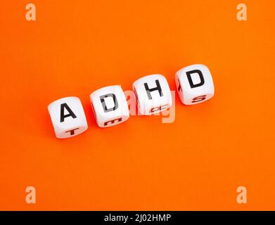 ADHD im Buchstabenwürfel auf orangefarbenem Hintergrund, die Farbe des ADHD-Bewusstseins ADHD im Buchstabenwürfel auf orangefarbenem Hintergrund, die Farbe des ADHD-Bewusstseins Stockfoto