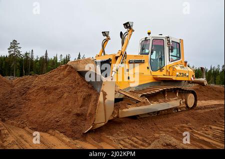 Ein gelber Traktor legt den Standort mit Sand ab Stockfoto