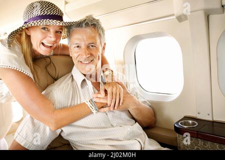 Ich freue mich schon auf den Urlaub. Lächelndes Seniorenpaar in einem Flugzeug auf dem Weg nach Übersee - Porträt. Stockfoto