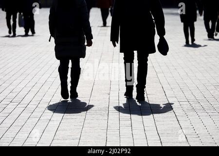 Silhouetten und Schatten von Menschen auf der Straße der Stadt. Menschenmenge, die auf dem Bürgersteig, dem Konzept von Fremden, Kriminalität, Gesellschaft oder Bevölkerung hinuntergeht Stockfoto