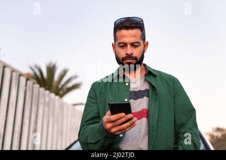 Hübscher junger Mann mit Bart, Mobiltelefon, Freizeit- und Kommunikationstechnologie-Konzept, Platz für Text kopieren Stockfoto