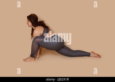 Zielorientiert übergewichtige übergewichtige Frau macht Sport Stretch, sitzt halb Splits. Wirbelsäule und Muskeln. Kalorien verbrennen Stockfoto