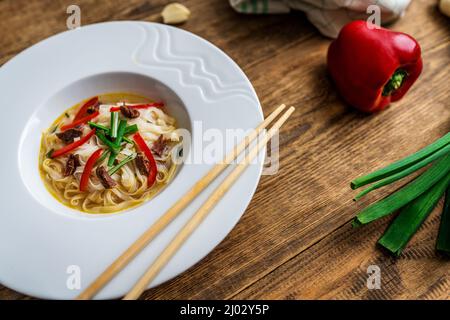 Vietnamesische Suppe Pho bo mit asiatischen Nudeln und Rindfleisch auf Holztisch Stockfoto