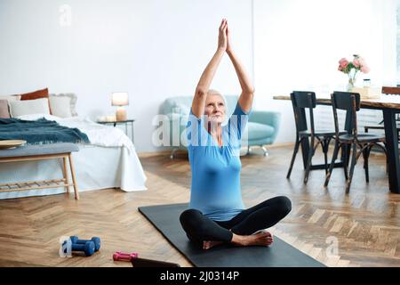 Ältere Frau, die mit einem Online-Trainer Übungen macht. Stockfoto