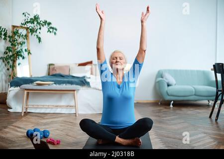 Ältere Frau, die mit einem Online-Trainer Übungen macht. Stockfoto