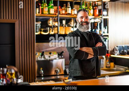 Porträt eines fröhlichen Sushi-Küchenchefs im Sushi-Restaurant. Er zeigt Daumen nach oben. Stockfoto