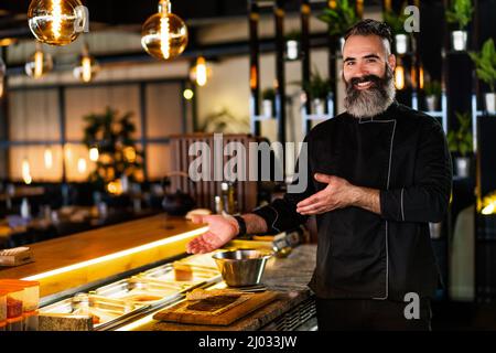 Porträt eines fröhlichen Sushi-Küchenchefs im Sushi-Restaurant. Stockfoto