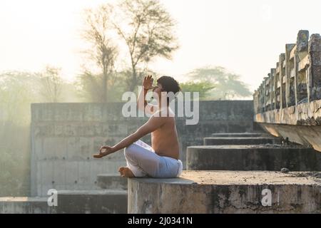 Junger indischer Mann, der früh am Morgen Yoga macht Stockfoto