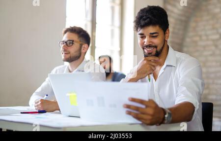 Gruppe von glücklichen multiethnischen Geschäftsleuten, die zusammenarbeiten und an Treffen im Büro der Firma arbeiten Stockfoto