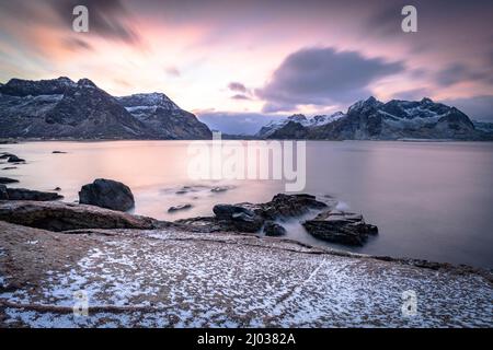 Wolken im Morgengrauen über dem kalten Meer und Vareid Strand mit Schnee bedeckt, Flakstad, Nordland County, Lofoten Islands, Norwegen, Skandinavien, Europa Stockfoto