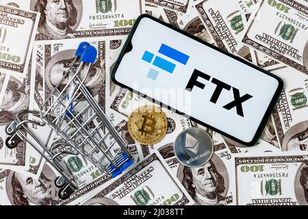 FTX ist eine Kryptowährungsbörse. Ein Smartphone mit dem FTX-Logo, einem Einkaufswagen und einer Kryptocoins auf den Dollarscheinen. Stockfoto