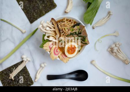 Eine Schüssel Ramen-Suppe mit allen Zutaten auf einem Marmortisch Stockfoto