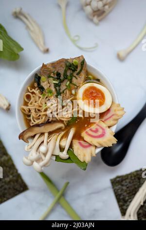 Eine Schüssel Ramen-Suppe mit allen Zutaten auf einem Marmortisch Stockfoto