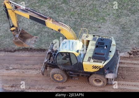 Ein Radlader gräbt auf einer Baustelle den Boden, um eine Straße zu pflastern Stockfoto