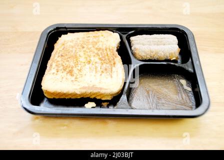 Gefrorene vorgekochte Mikrowelle Frühstück mit französischem Toast, Ahornsirup und Würstchen Links Stockfoto