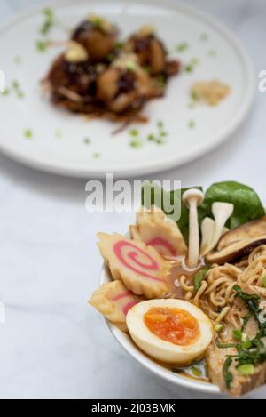 Eine Schüssel mit Ramen-Suppe und ein Teller Takoyaki-Snack Stockfoto