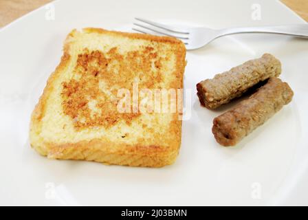 Gebratener französischer Toast auf einem Teller mit zwei Wurstwaren-Links Stockfoto