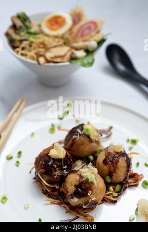 Eine Schüssel mit Ramen-Suppe und ein Teller Takoyaki-Snack Stockfoto